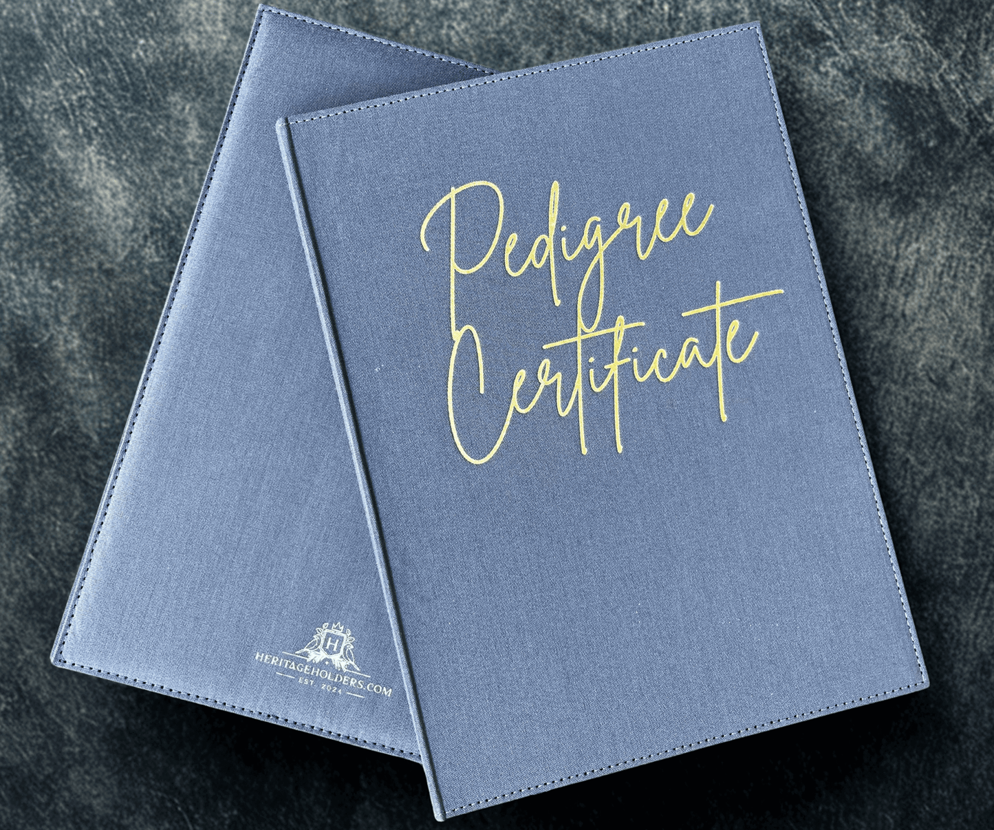 Two blue 'Pedigree Certificate' folders on a dark textured surface