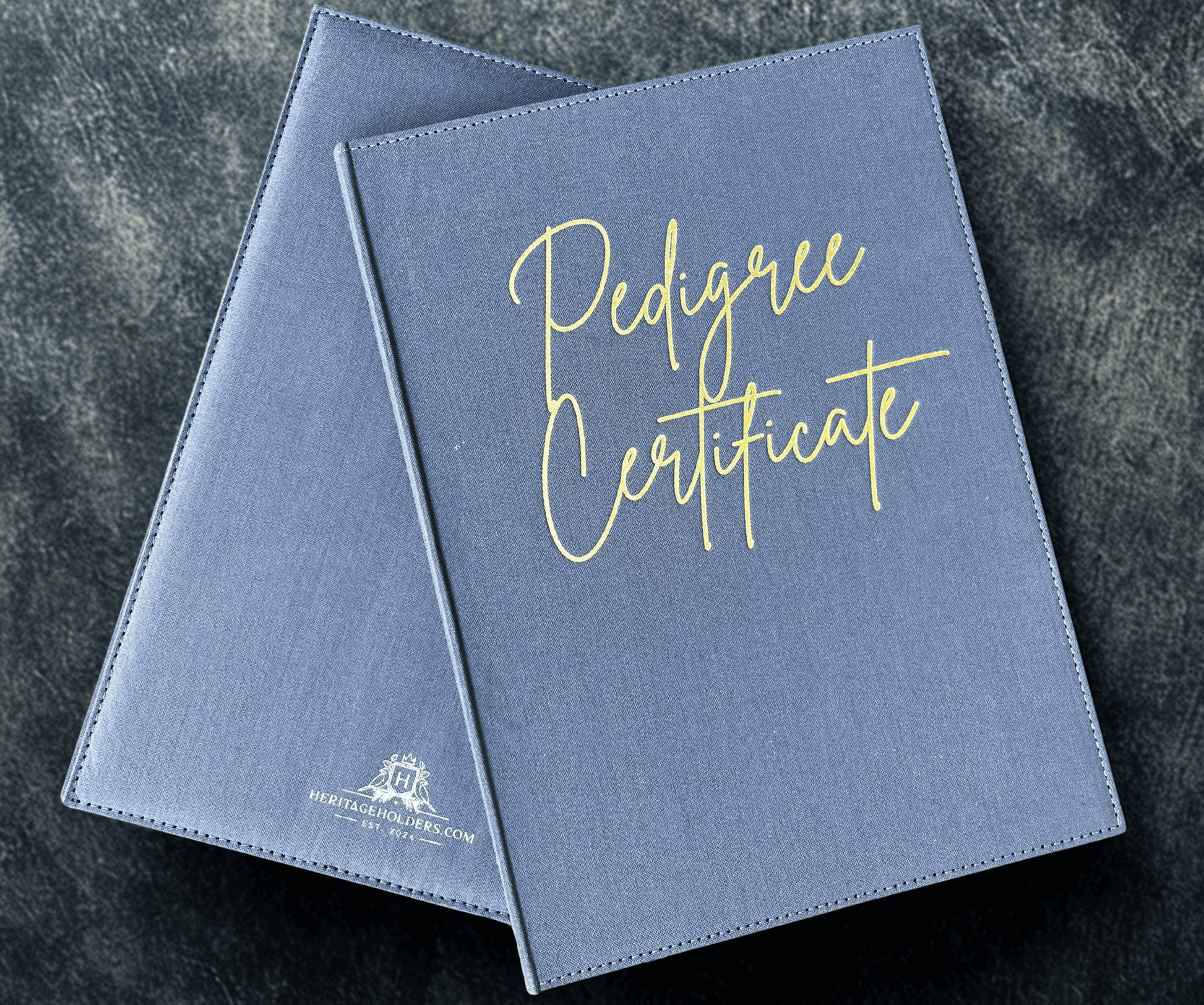 Two blue 'Pedigree Certificate' folders on a dark textured surface